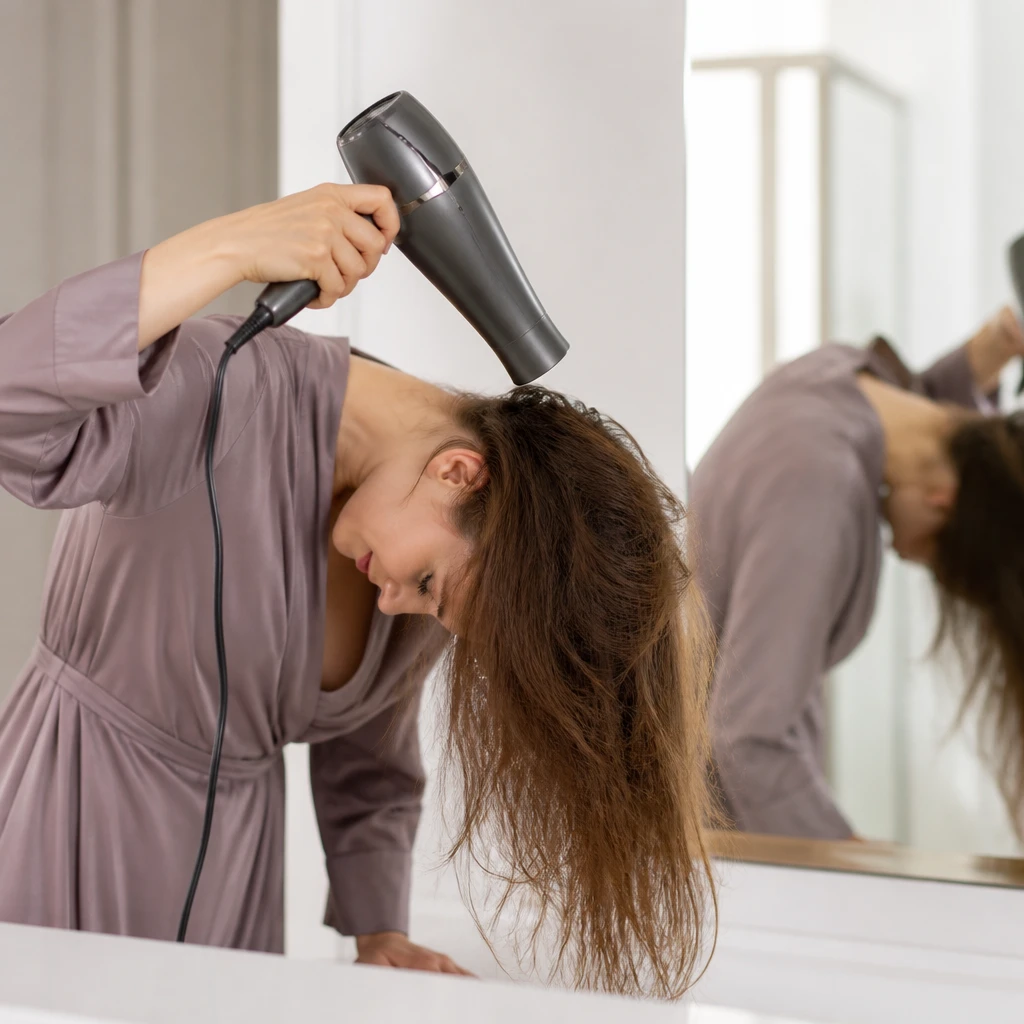 woman with thin hair blow drying head upside down for root volume at home tutorial concept editorial beauty photography